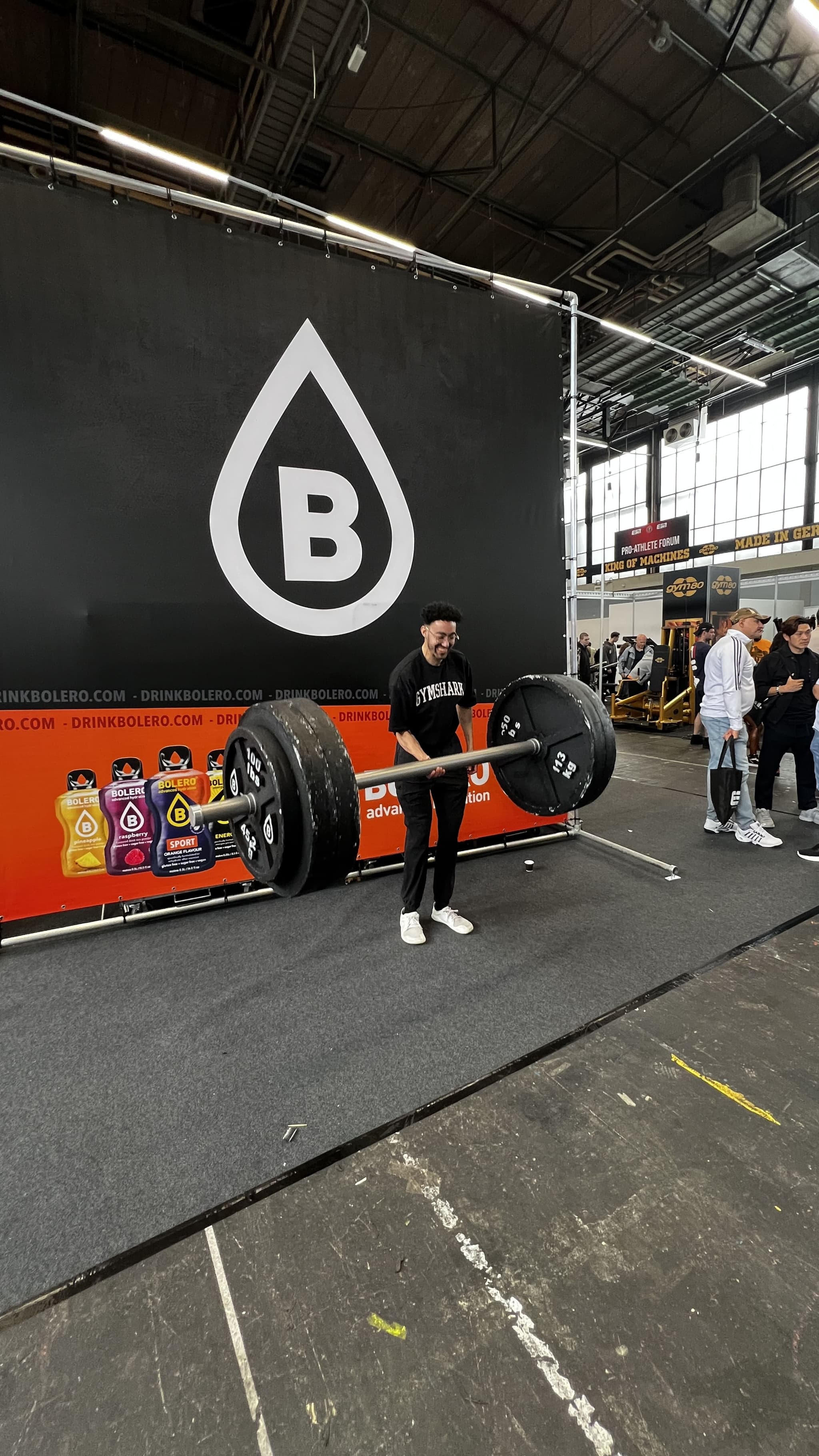 Fitness boy holding a massive barbell with foam plates at a fitness expo